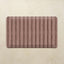 Maroon kitchen mat with striped pattern on a beige background