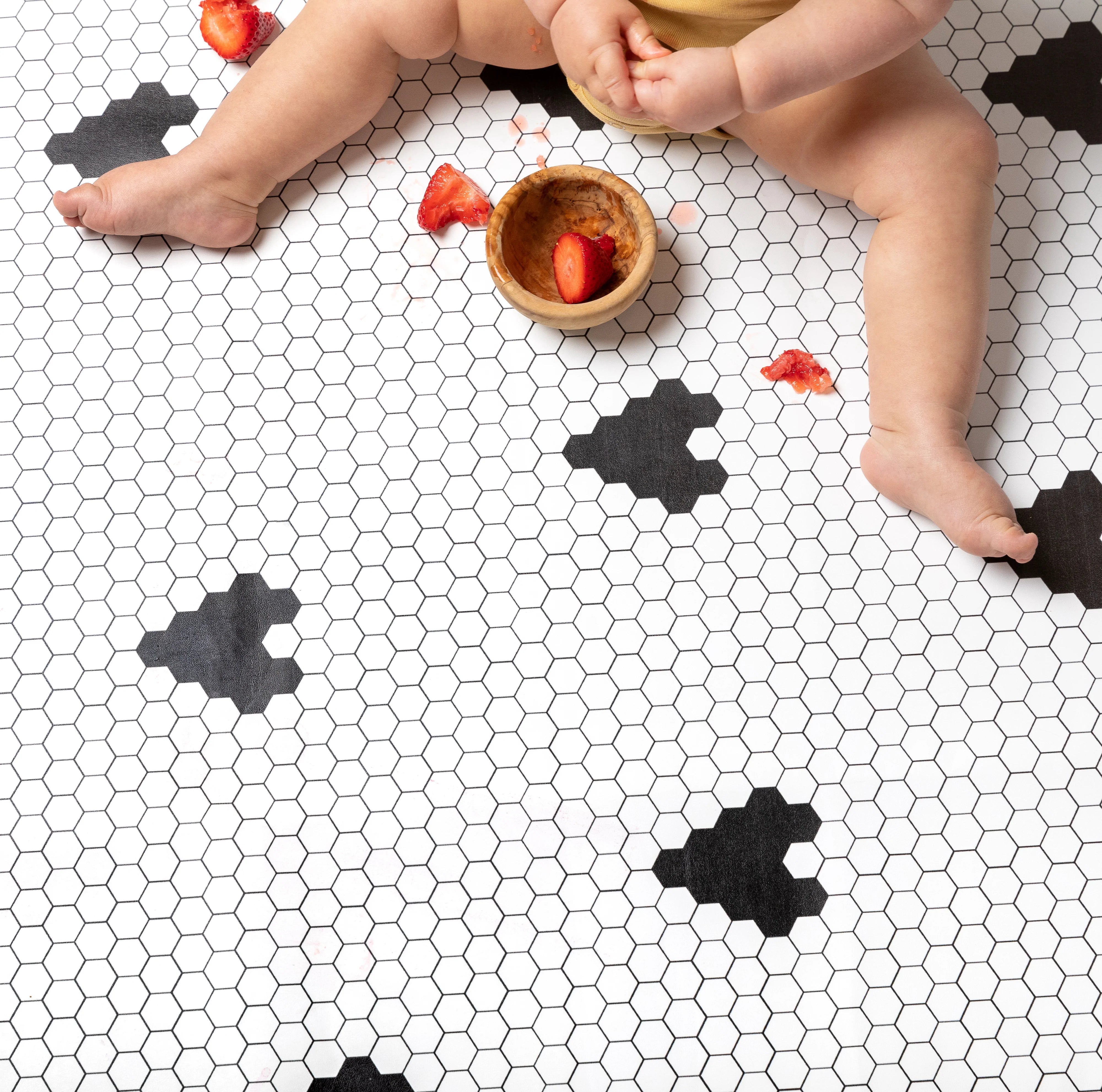 Penny Tile Black and White Heart pattern highchair mat with baby eating strawberries