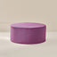 A round upholstered ottoman or pouf with a lid, featuring vertical stripes in bright blue and orange-red, set against a minimalist beige background.