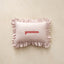 Striped pillow with ruffles and 'genevieve' embroidery on a beige background