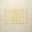 Yellow bath mat with white stripes on a beige background