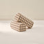 Two grid patterned arch cylindrical armrest pillows from House of Noa in wheat and sable from House of Noa