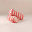 Two cylindrical red and white striped fabric armrests upright on a light beige surface against a matching beige background.