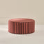 Round ottoman with red and black striped pattern on a beige background