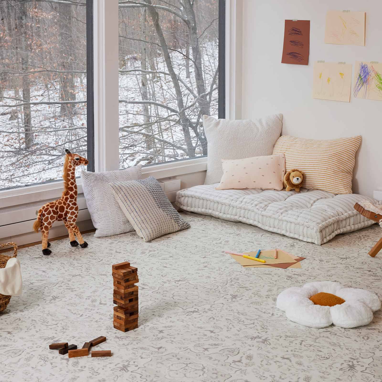 Emile latte neutral floral play mat shown in play room with various toys and pillows on top of the mat