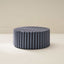 A cylindrical soft furniture ottoman with beige and white checkered fabric upholstery.