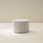 A cylindrical soft furniture ottoman with beige and white checkered fabric upholstery.