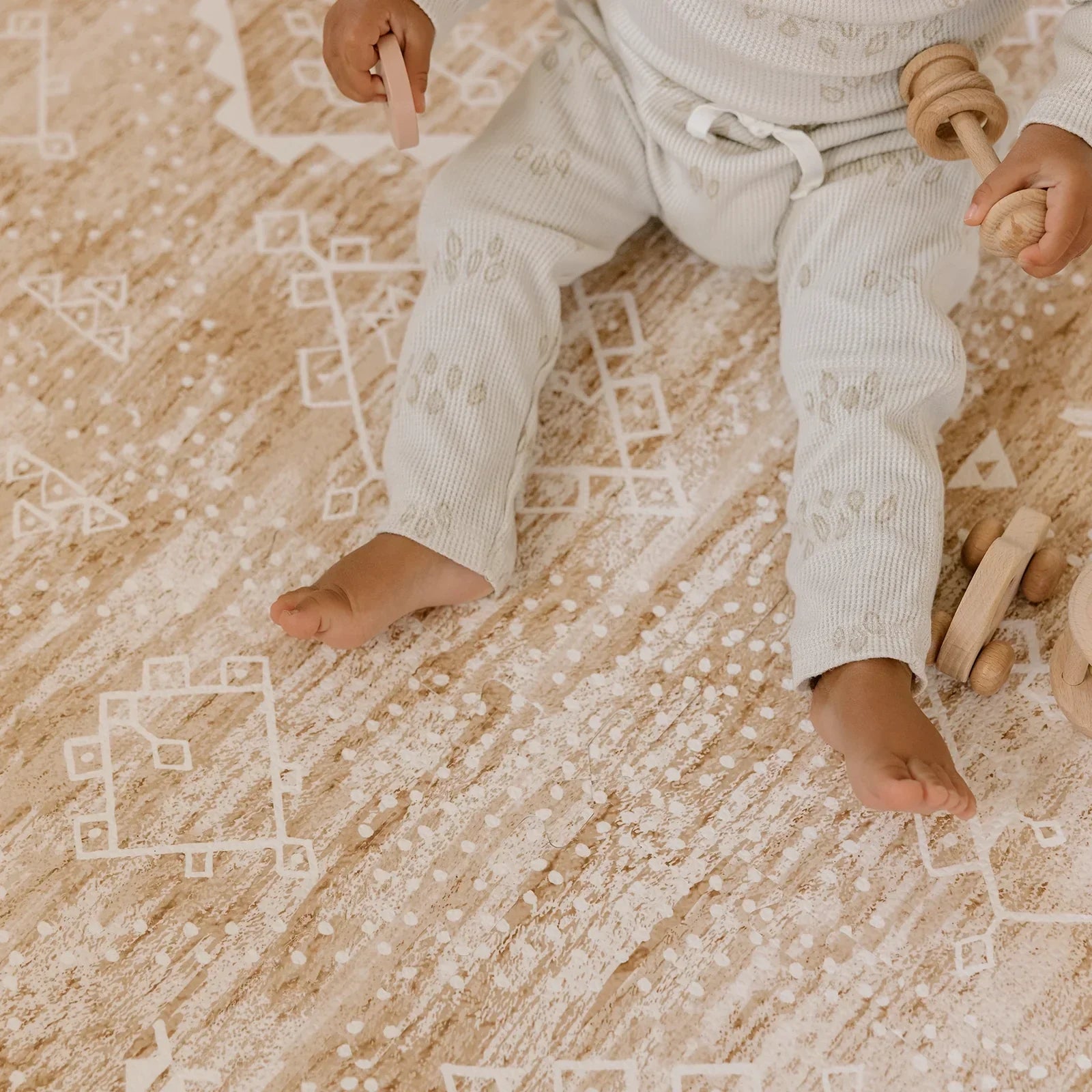 Ula Amber brown minimal boho pattern play mat with babies feet and hands playing with wooden toys