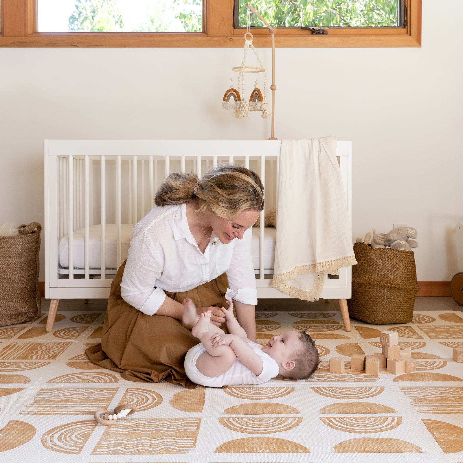 Ada modern minimalist baby play mat in Sunflower, mustard yellow and off white. Shown in a nursery with Mom and baby playing.