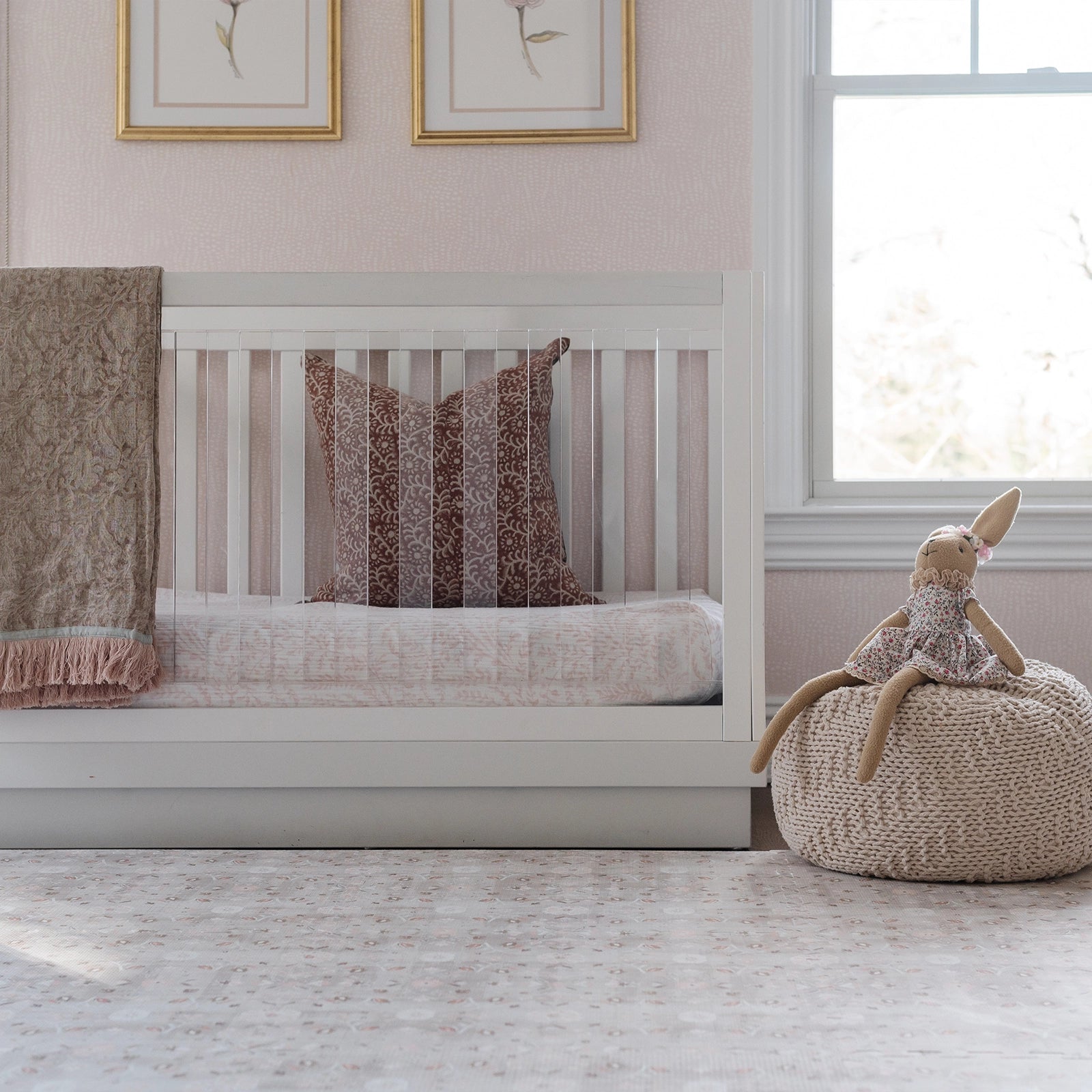 Linen beige and light pink floral baby play mat in nursery with crib and bunny stuffed animal