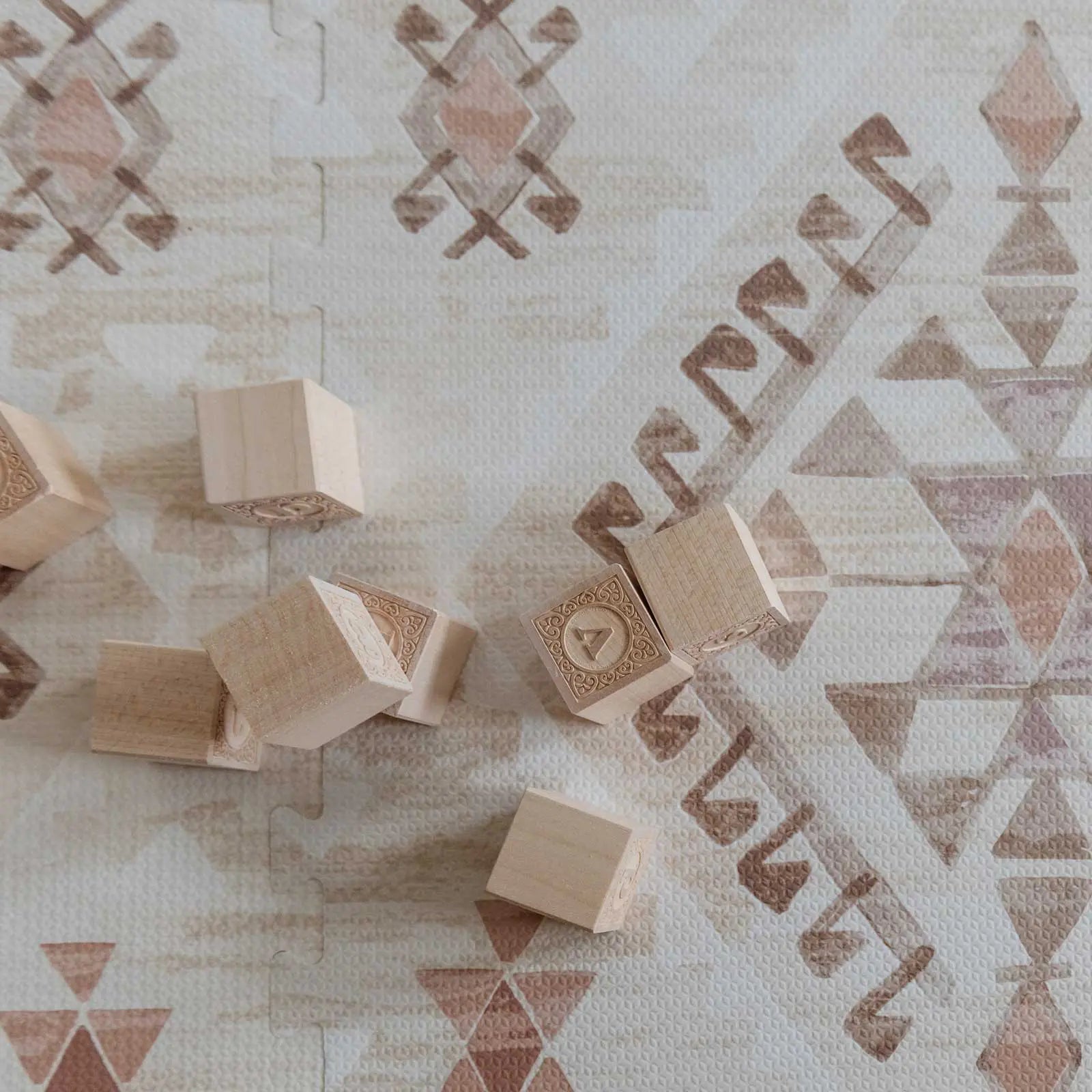 Nalla Mojave neutral beige brown and pink boho print play mat close up shot of the print with wooden blocks on the mat