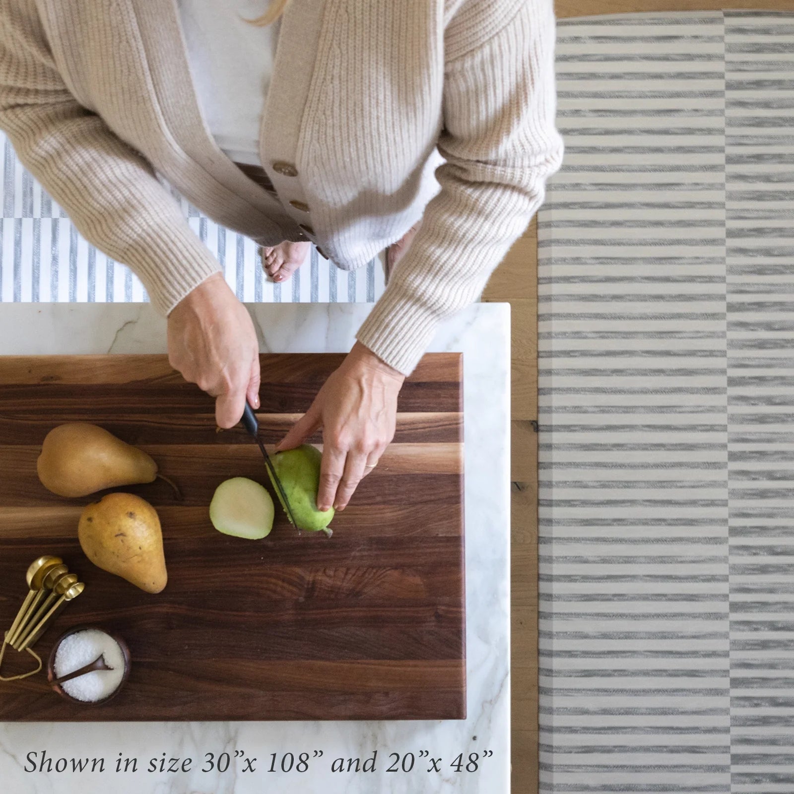 Reese pewter gray and white inverted stripe standing mat shown from above in kitchen in sizes 20x48 and 30x108 with woman cutting pears