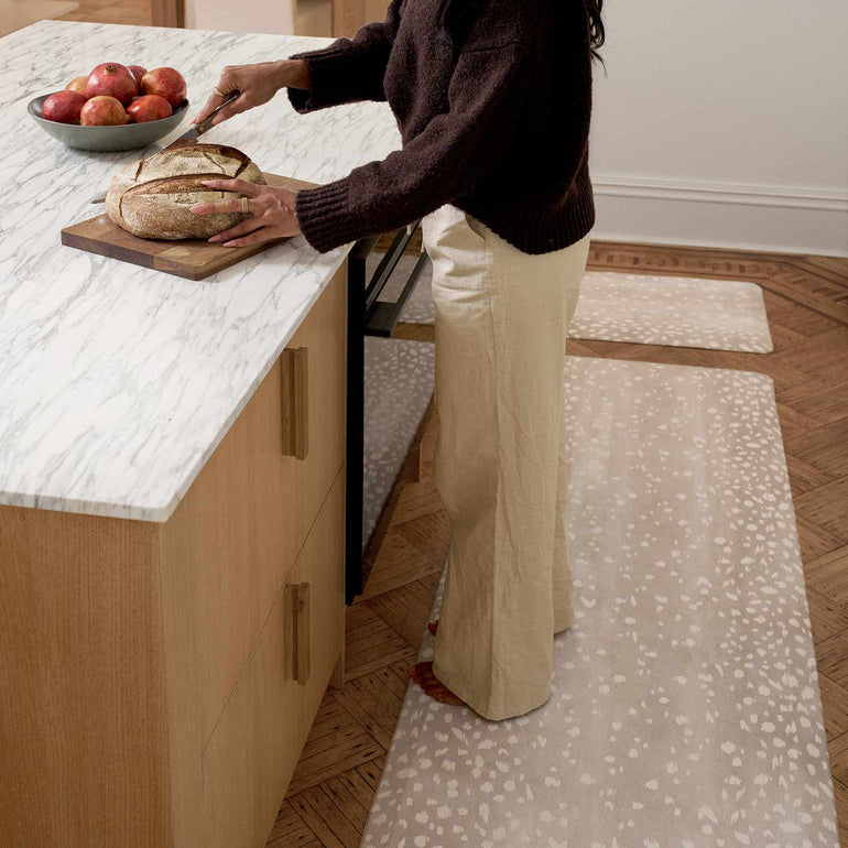 woman standing on anti fatigue kitchen mat cutting bread