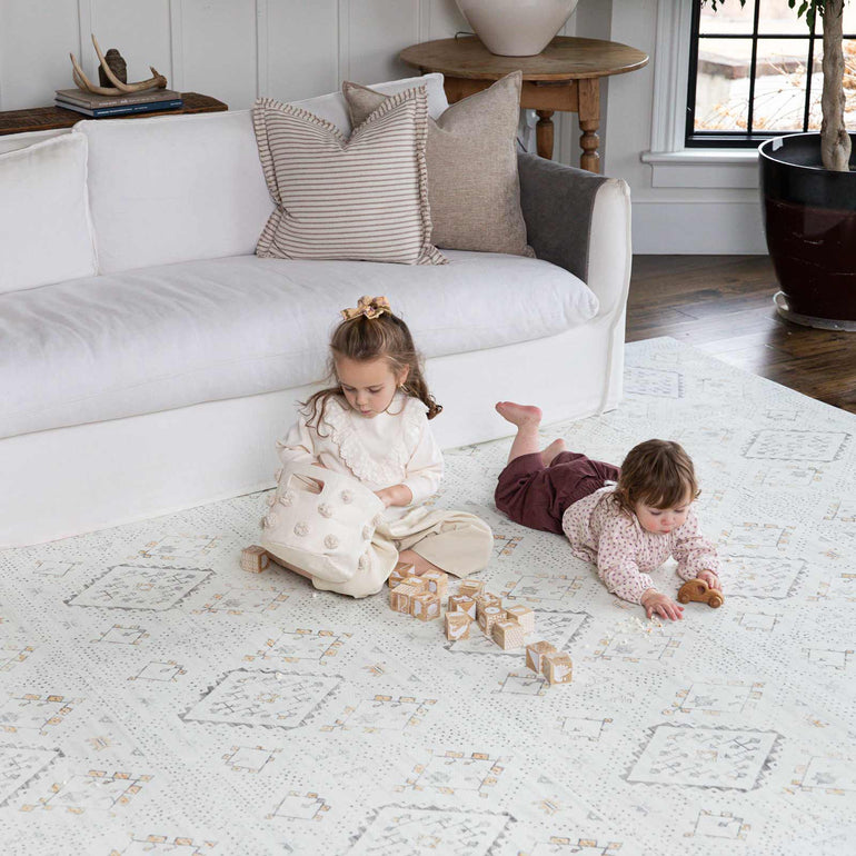 two children sitting and playing on house of noa play mat