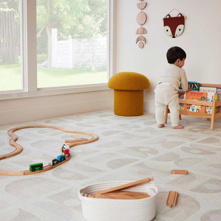 kid picking up a book from their messy playroom