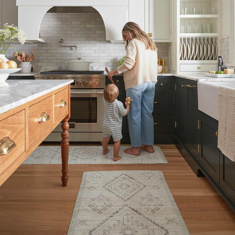 mom cooking with baby in the kitchen standing on top of house of noa anti fatigue standing mat