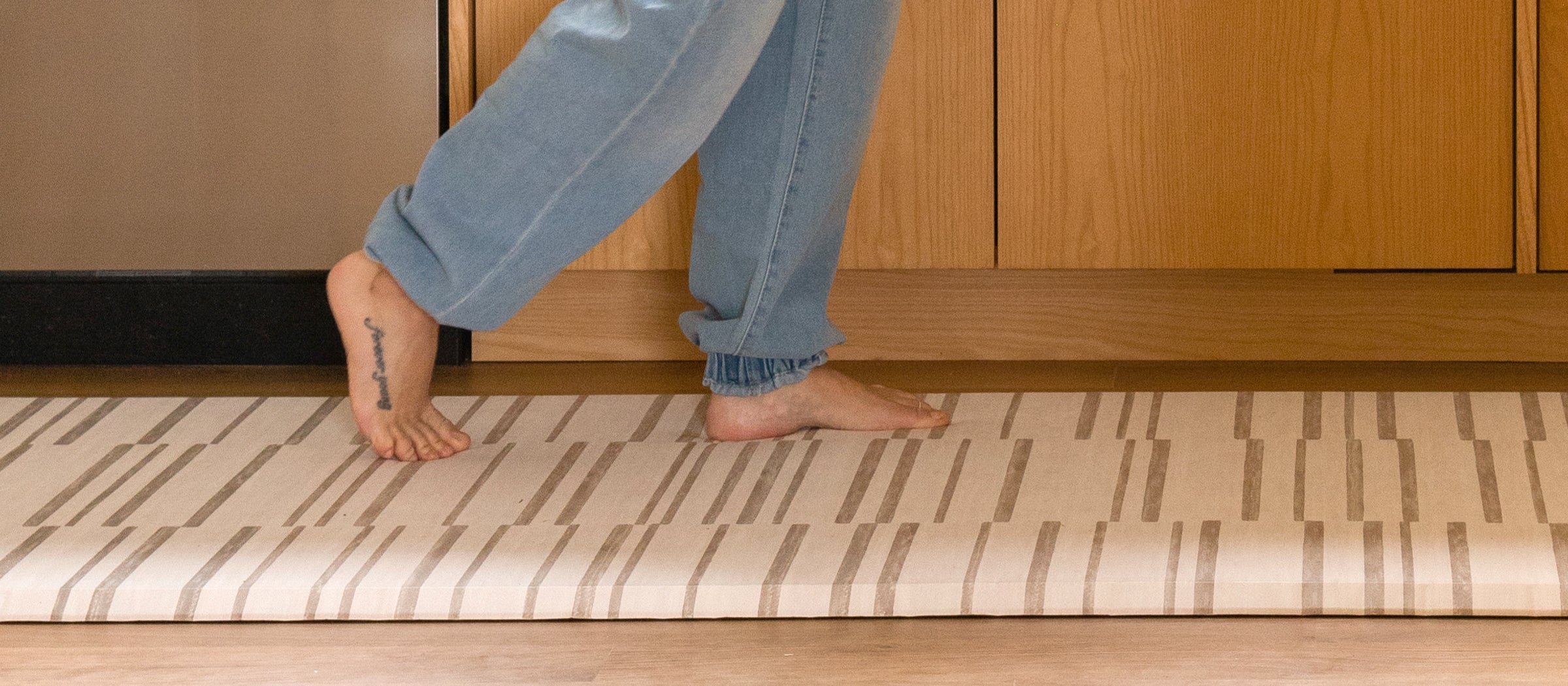 Nara Stripe Minimal Neutral Kitchen Mat with woman's feet
