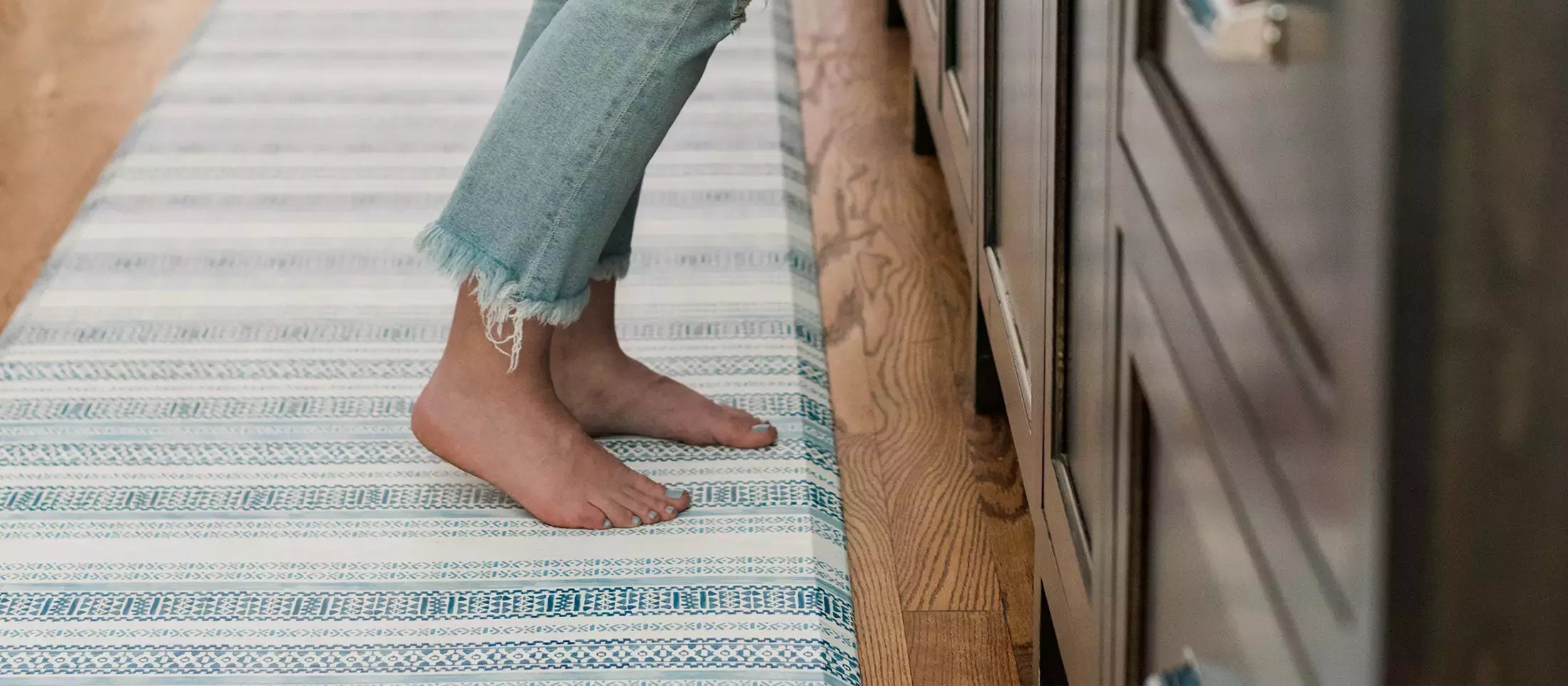 Paloma Blue and White Striped Boho Standing Mat with woman standing in kitchen