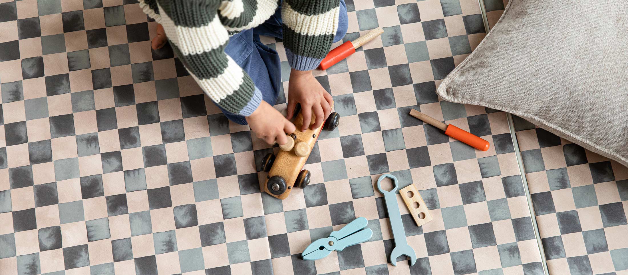 Checker Tuxedo black and white geometric tumbling mat shown with toddlers walking on the mat carrying a present with wooden blocks scattered across