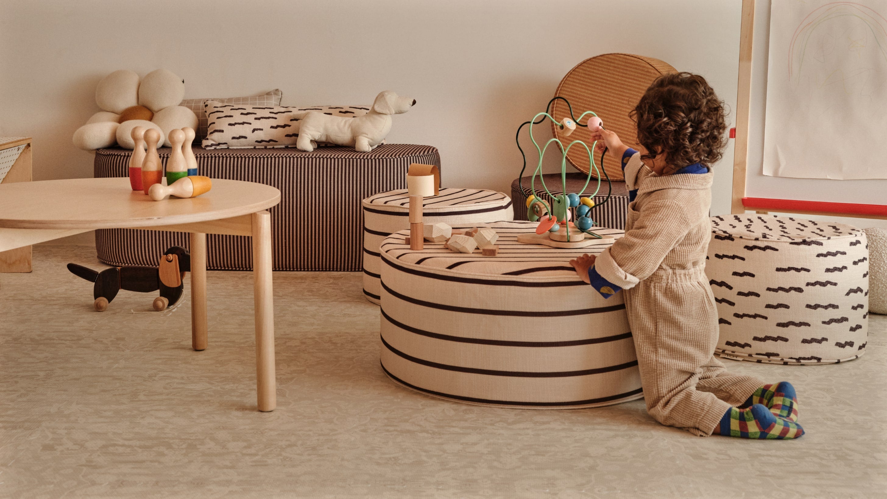 Toddler playing with toys in a play room with patterned ottomans