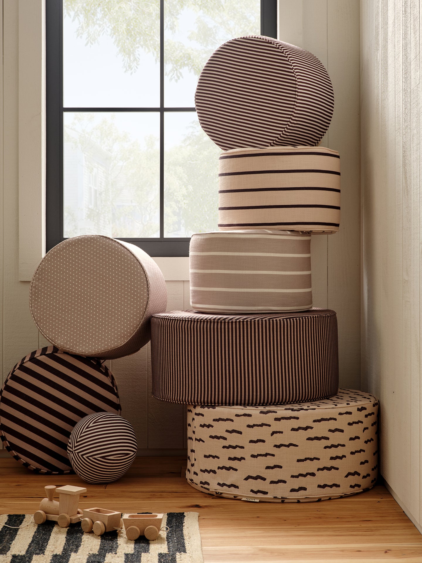 Stack of patterned ottomans in the corner of a room in front of a window.