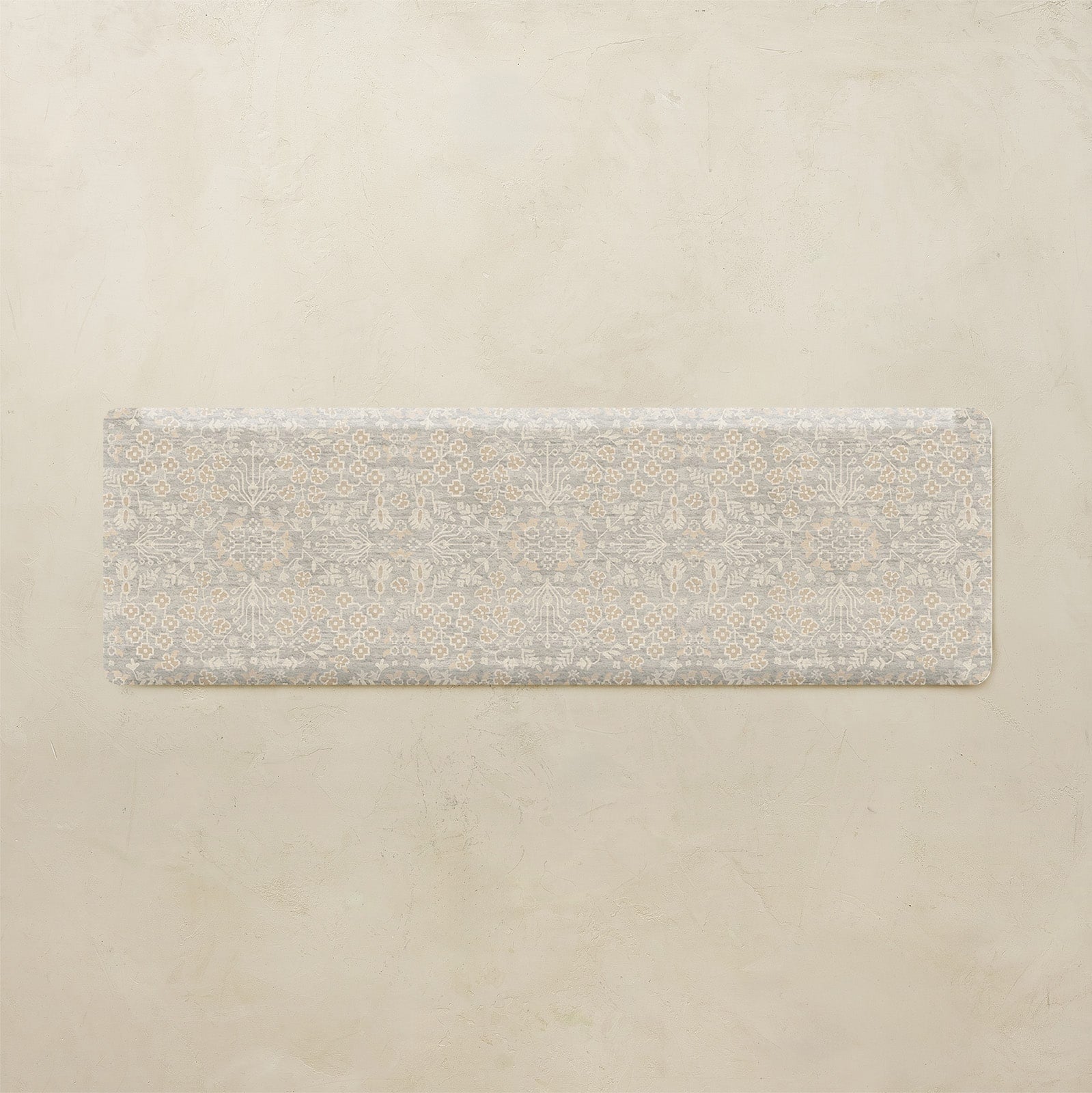 Rectangular rug with a subtle floral pattern on a beige background
