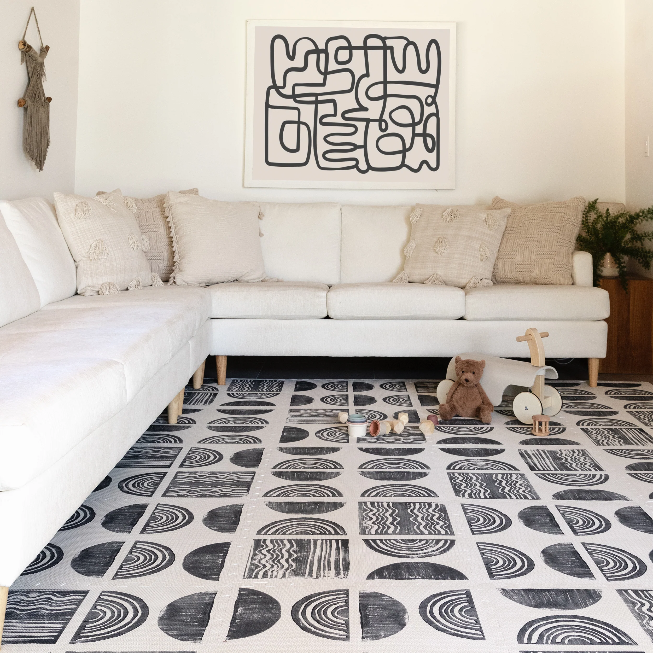 Ada modern minimalist baby play mat in Char, black and off white. Shown in living room with baby toys.