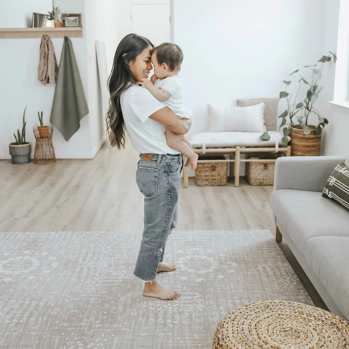 Sand Castle beige play mat shown in living room with Mom holding baby