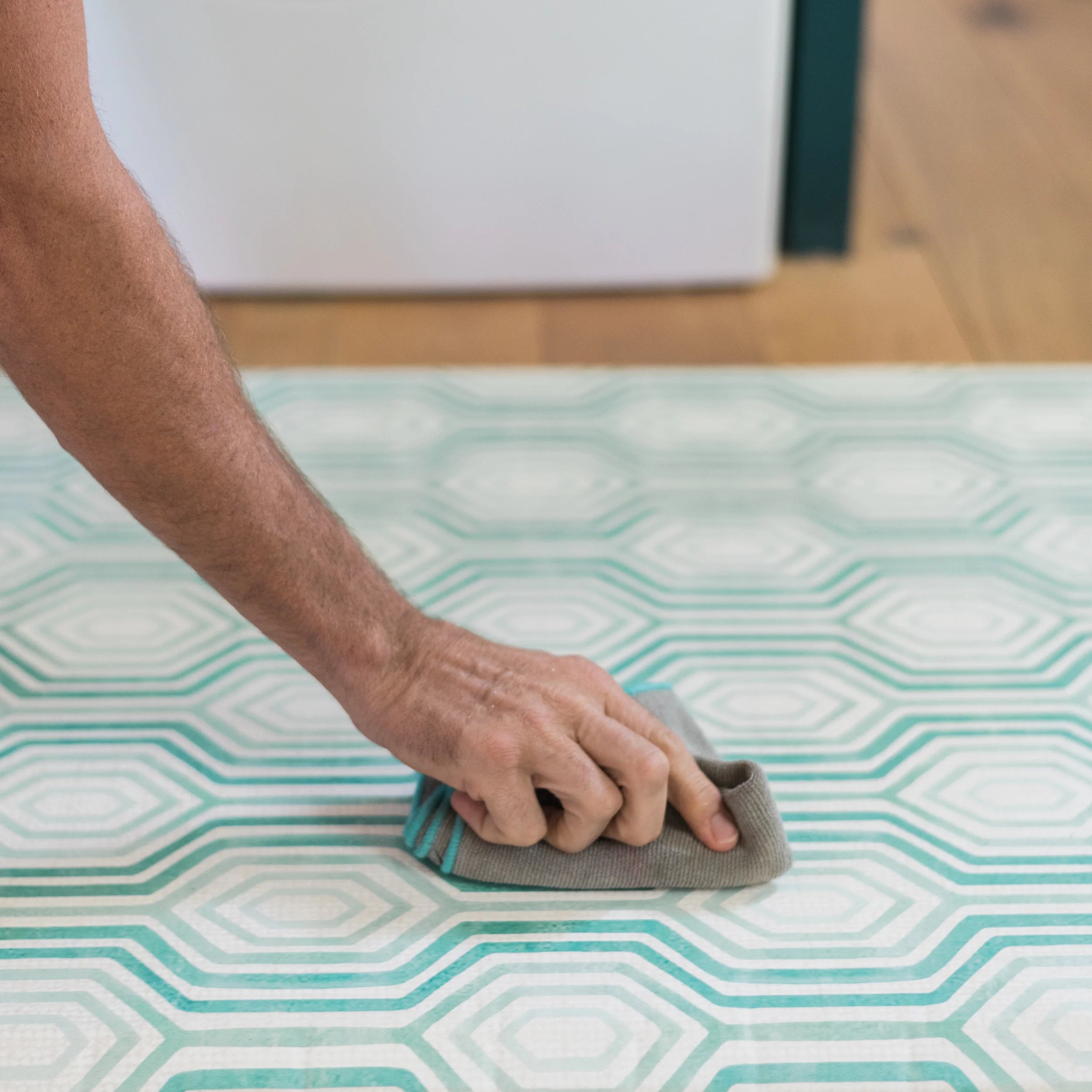 Blake soft emerald green geometric print kitchen mat with man's hand wiping up a spill