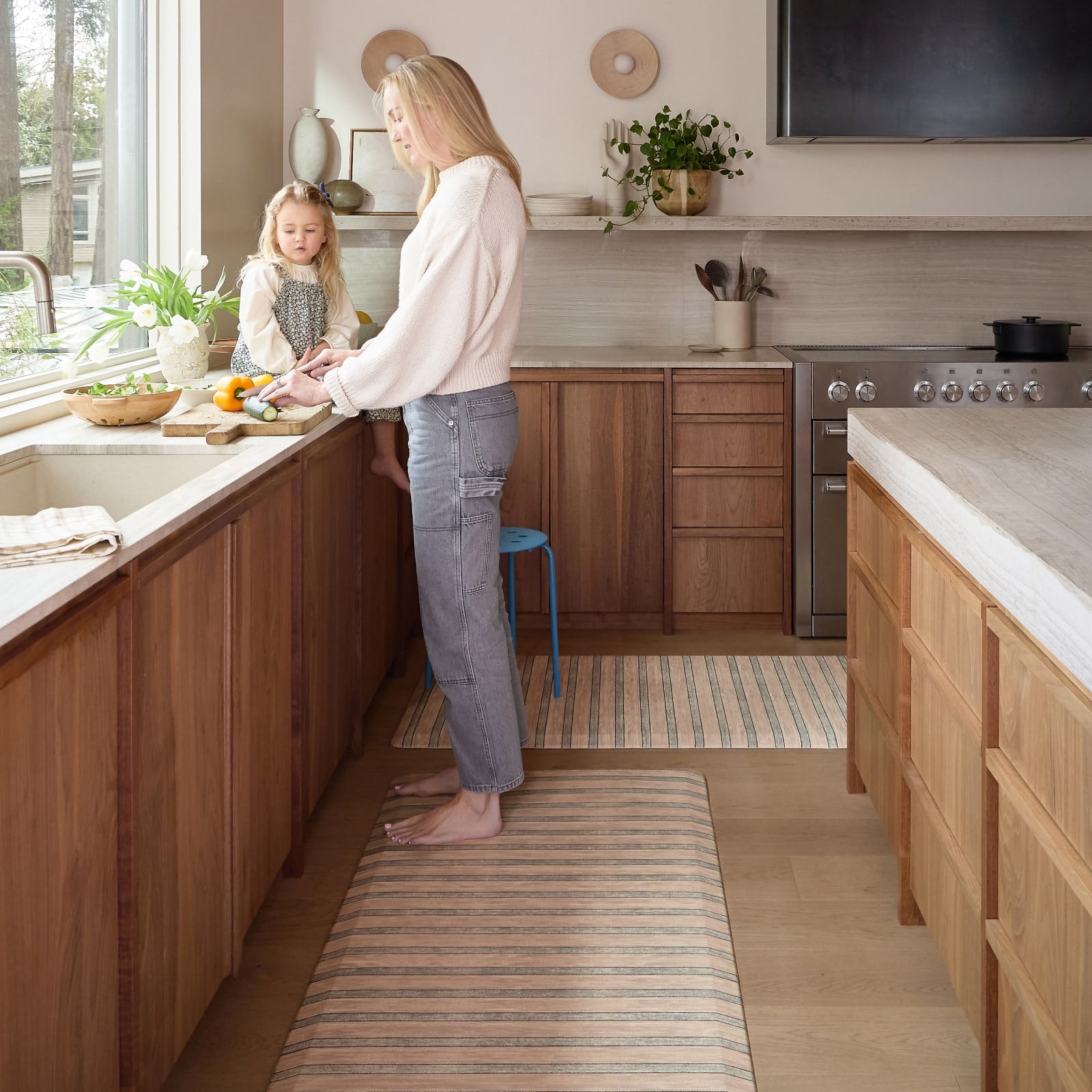 Woman and child in a kitchen preparing food together standing on a striped kitchen mat