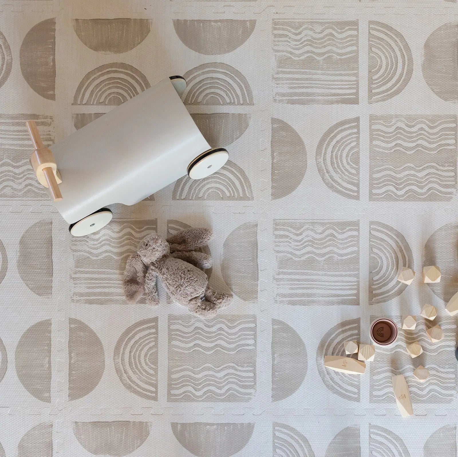 Ada modern minimalist baby play mat in Pebble taupe and off white. Shown from above with baby toys.