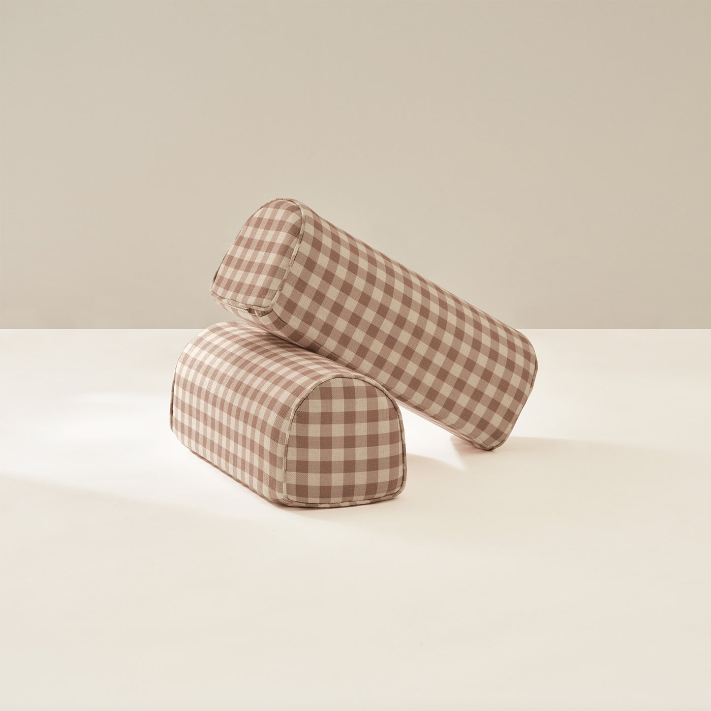 Two cylindrical checkered armrests on a light beige background
