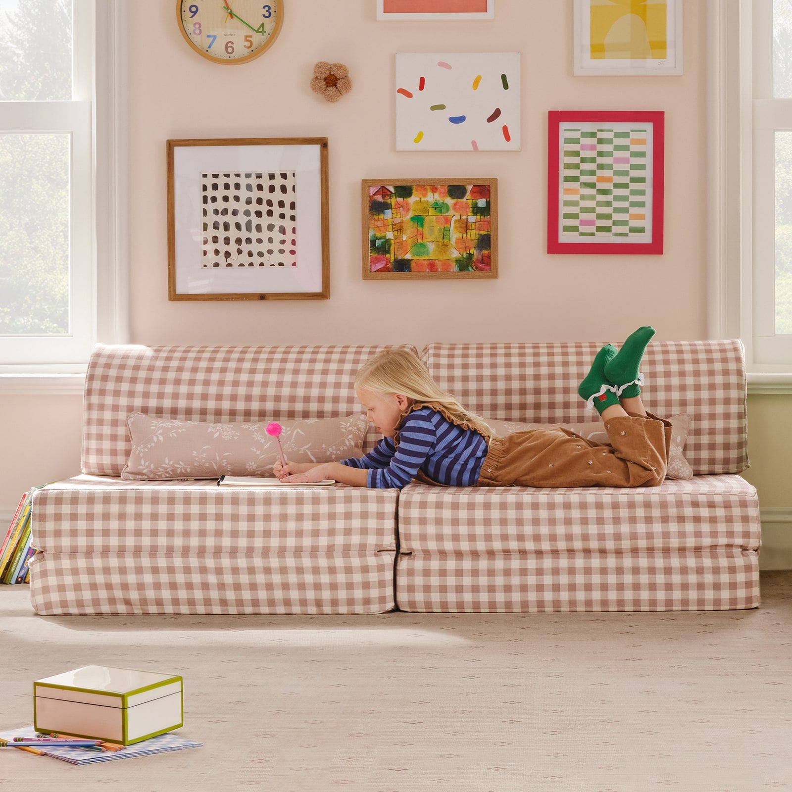 Child lying on a checkered sofa in a room with colorful artwork on the wall.