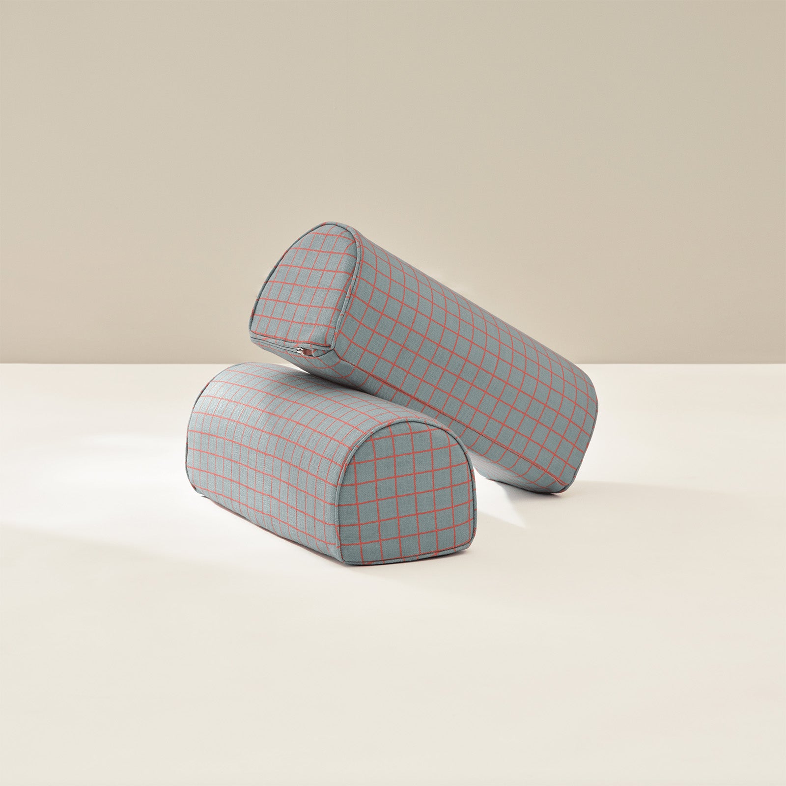 Two cylindrical armrests with a blue and orange grid pattern on a beige background