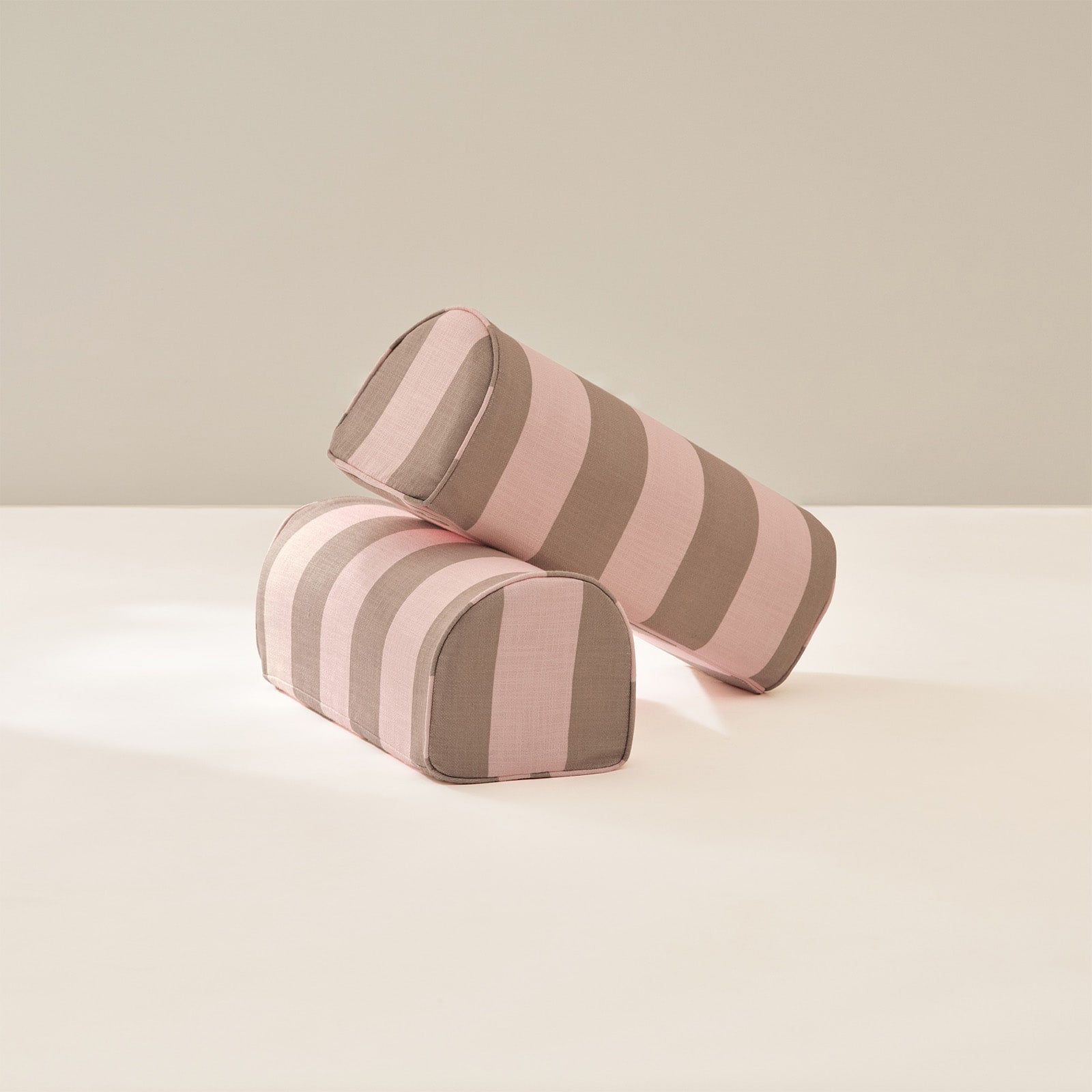 Two striped cylindrical armrests on a light beige background
