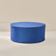 A round upholstered ottoman or pouf with vertical blue and navy stripes, shown on a clean beige studio background.