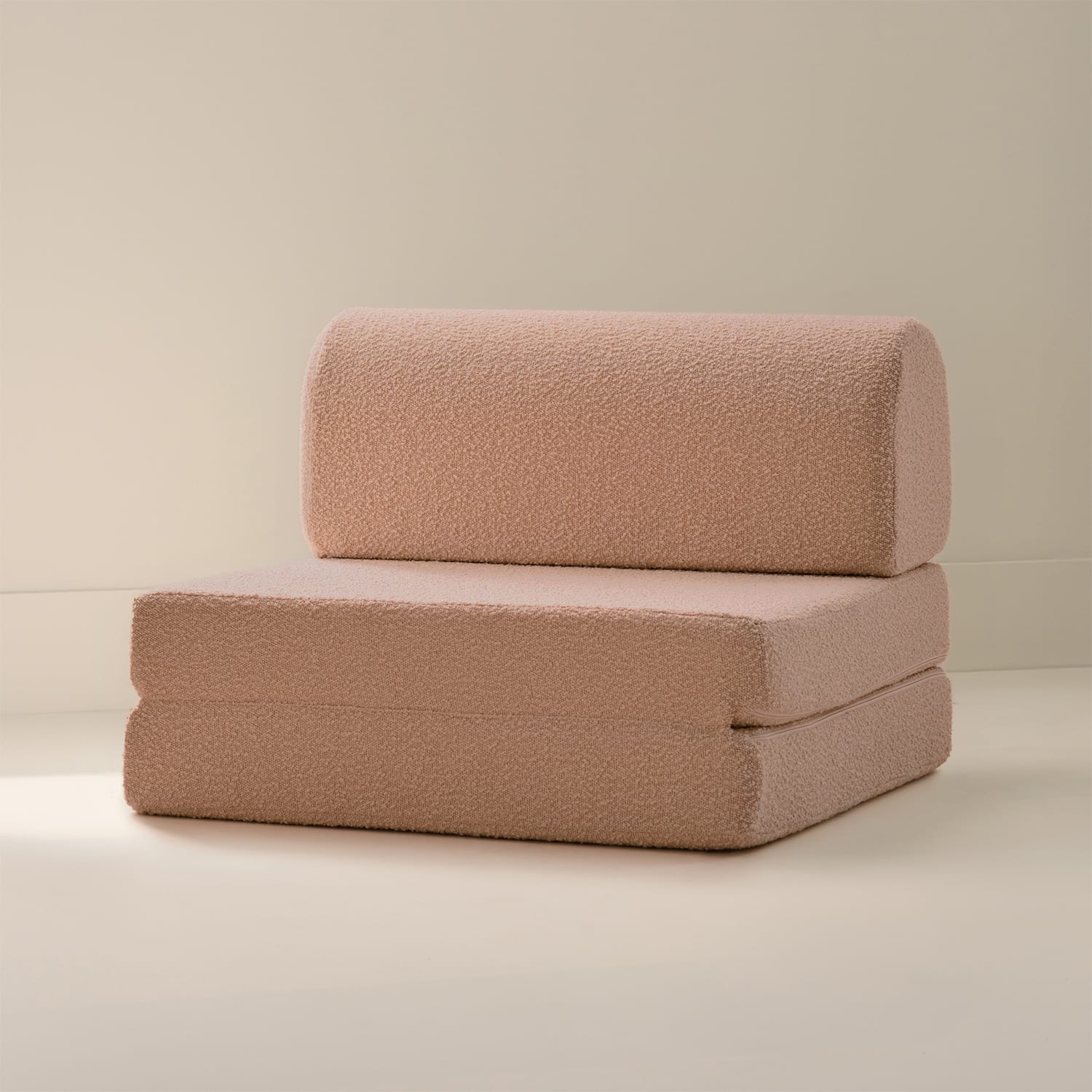 A pink boucle textured chair on a beige background.