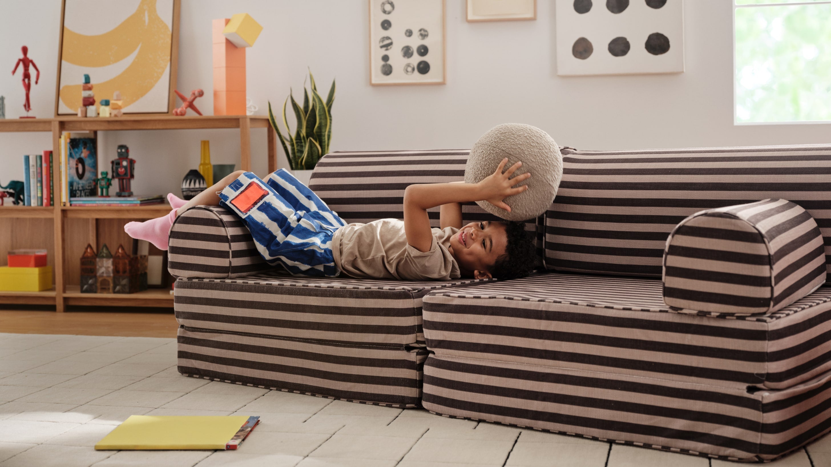 young boy laying on a brown and black striped play couch