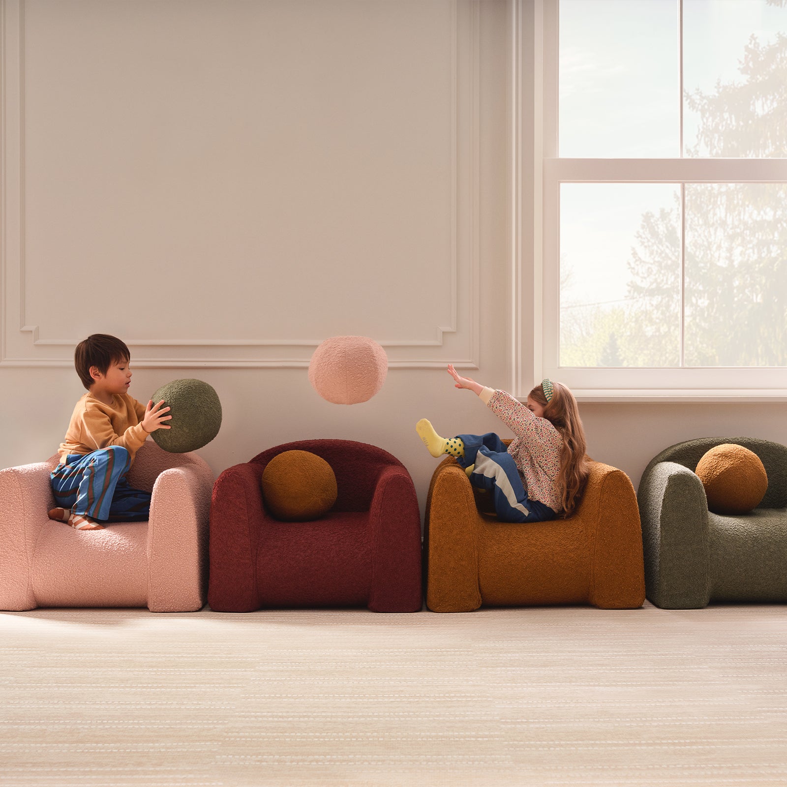 Children sitting in colorful Boucle Play Chairs playing with colorful round pillows