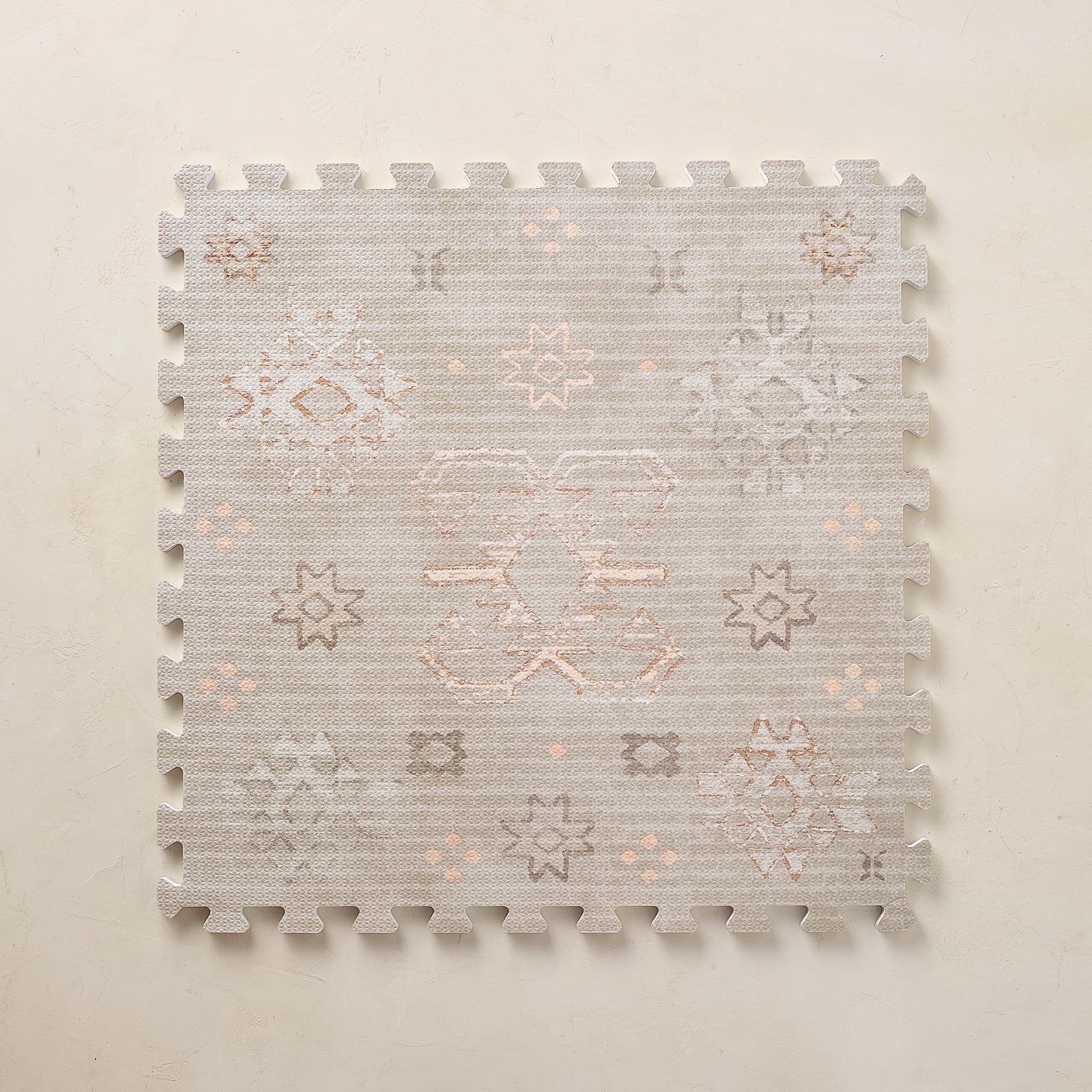 Patterned neutral play mat tile on a beige background