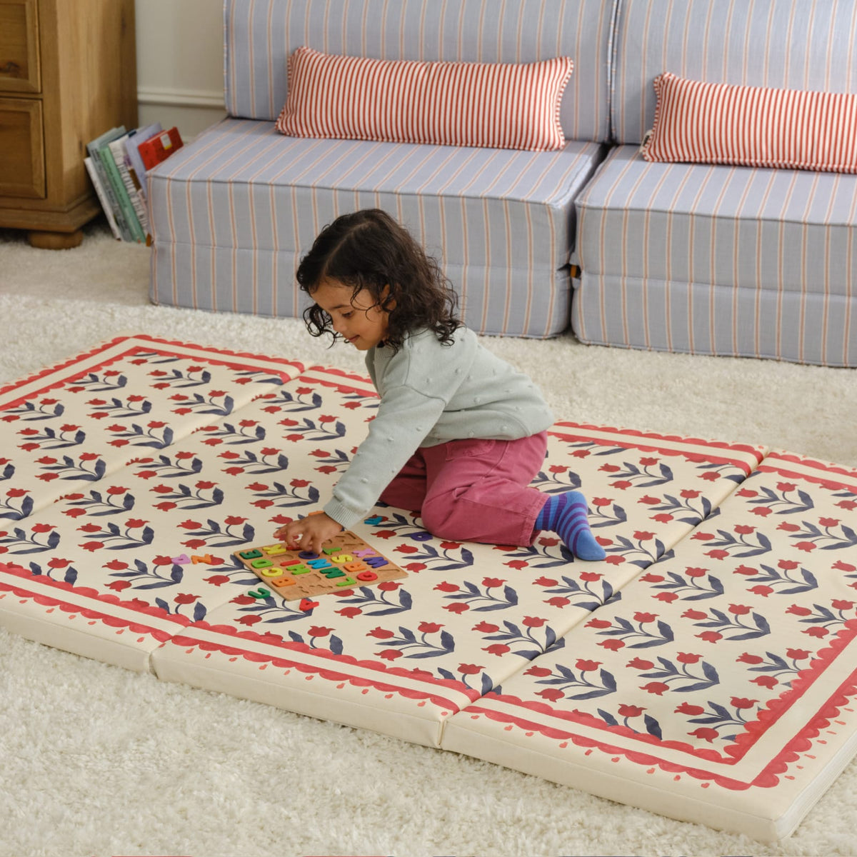 Toddler playing with a puzzle on the Delilah Carnation tumbling mat in a living room