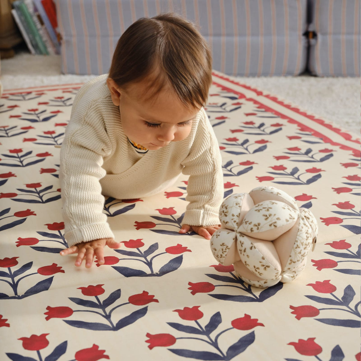 Baby crawling toward a soft ball on the red tulip Delilah Carnation tumbling mat