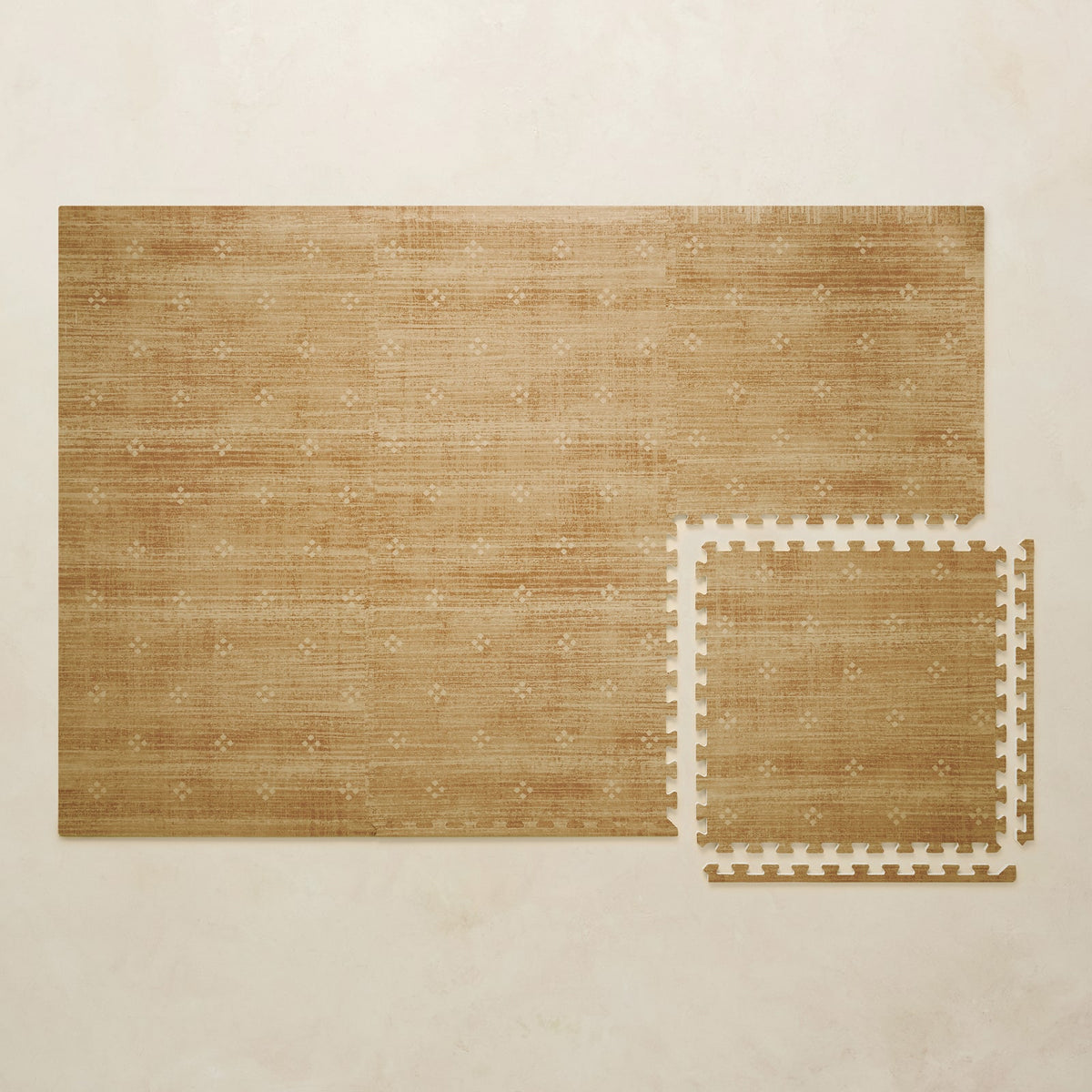A 4x6 mustard foam play mat shown beside a single interlocking tile to compare sizes, photographed from above on a beige background.