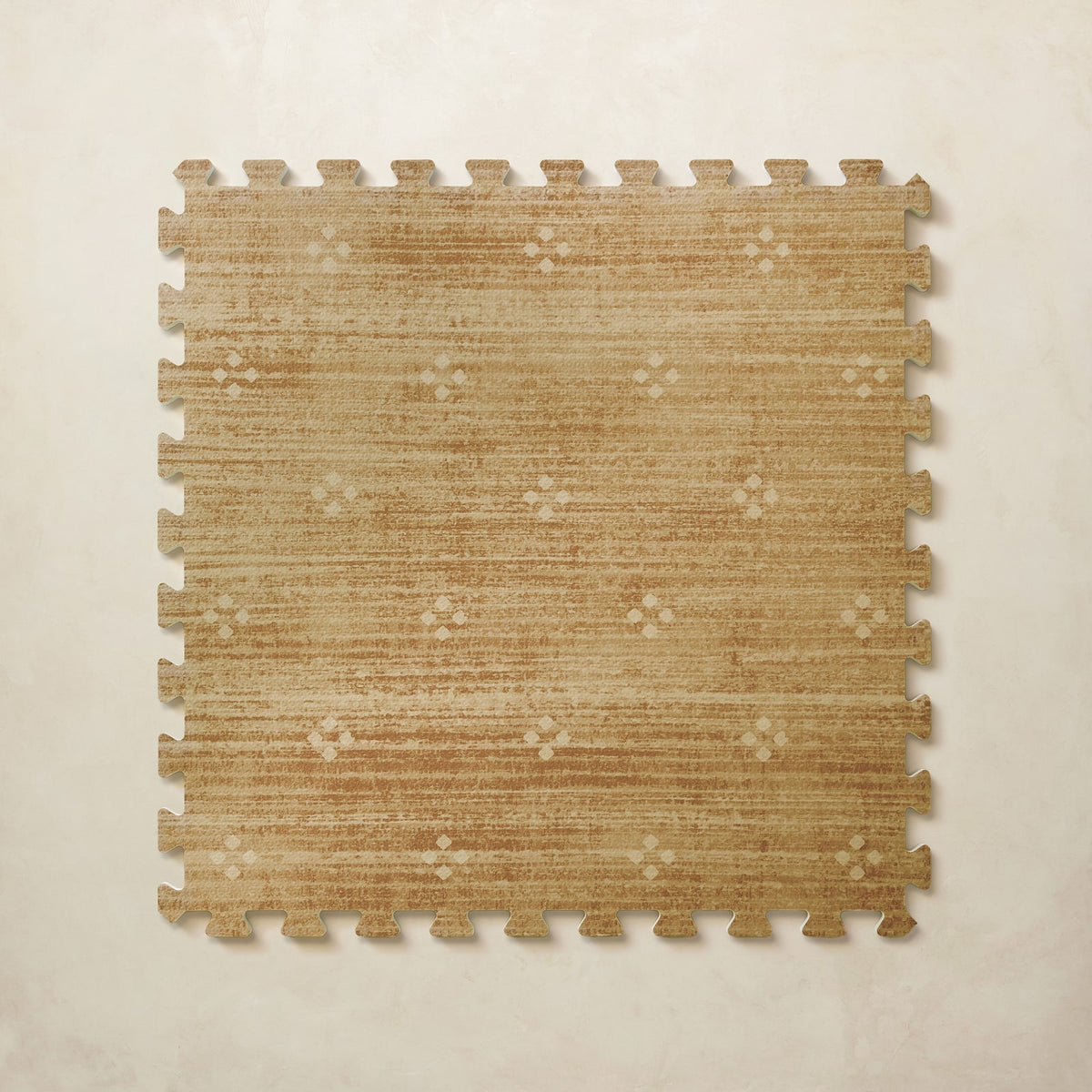 A square interlocking foam play mat tile in warm mustard with a scattered cream diamond dot motif, shown from above on a light beige background.