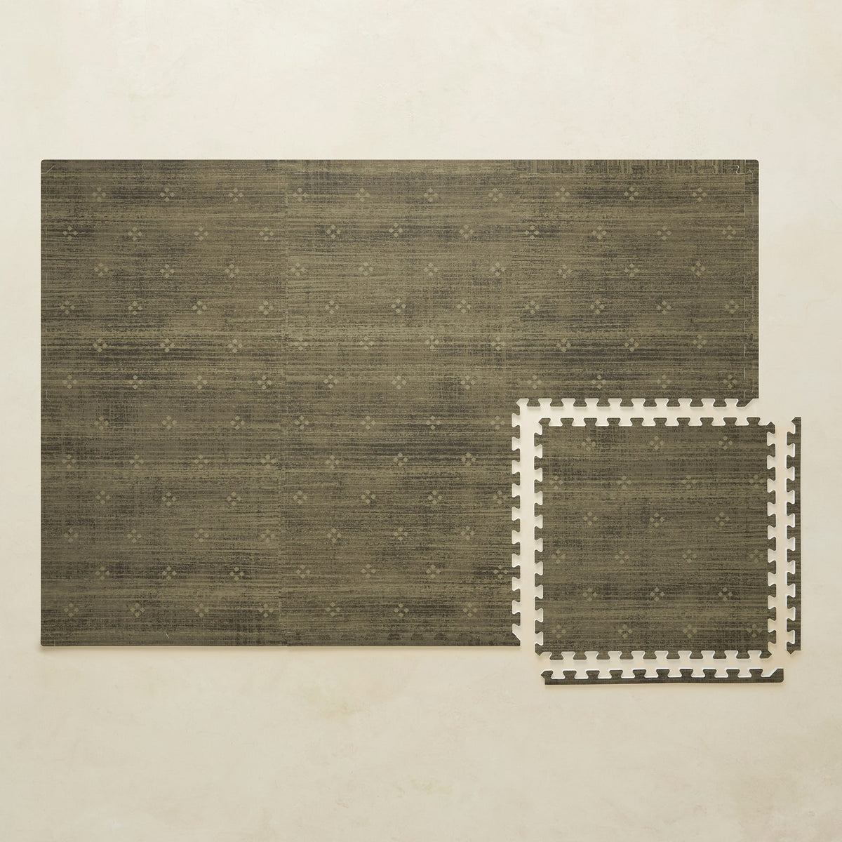 A 4x6 olive green foam play mat shown beside a single interlocking tile to compare sizes, photographed from above on a beige background.