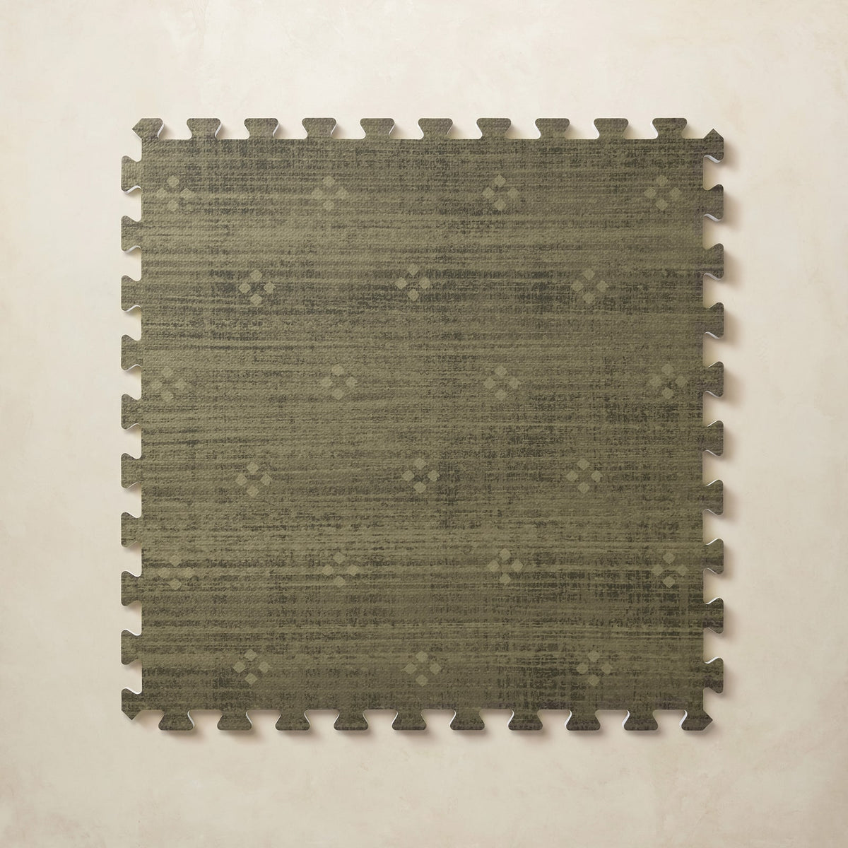 A square interlocking foam play mat tile in mossy olive green with a tonal diamond dot motif, shown from above on a light beige background.