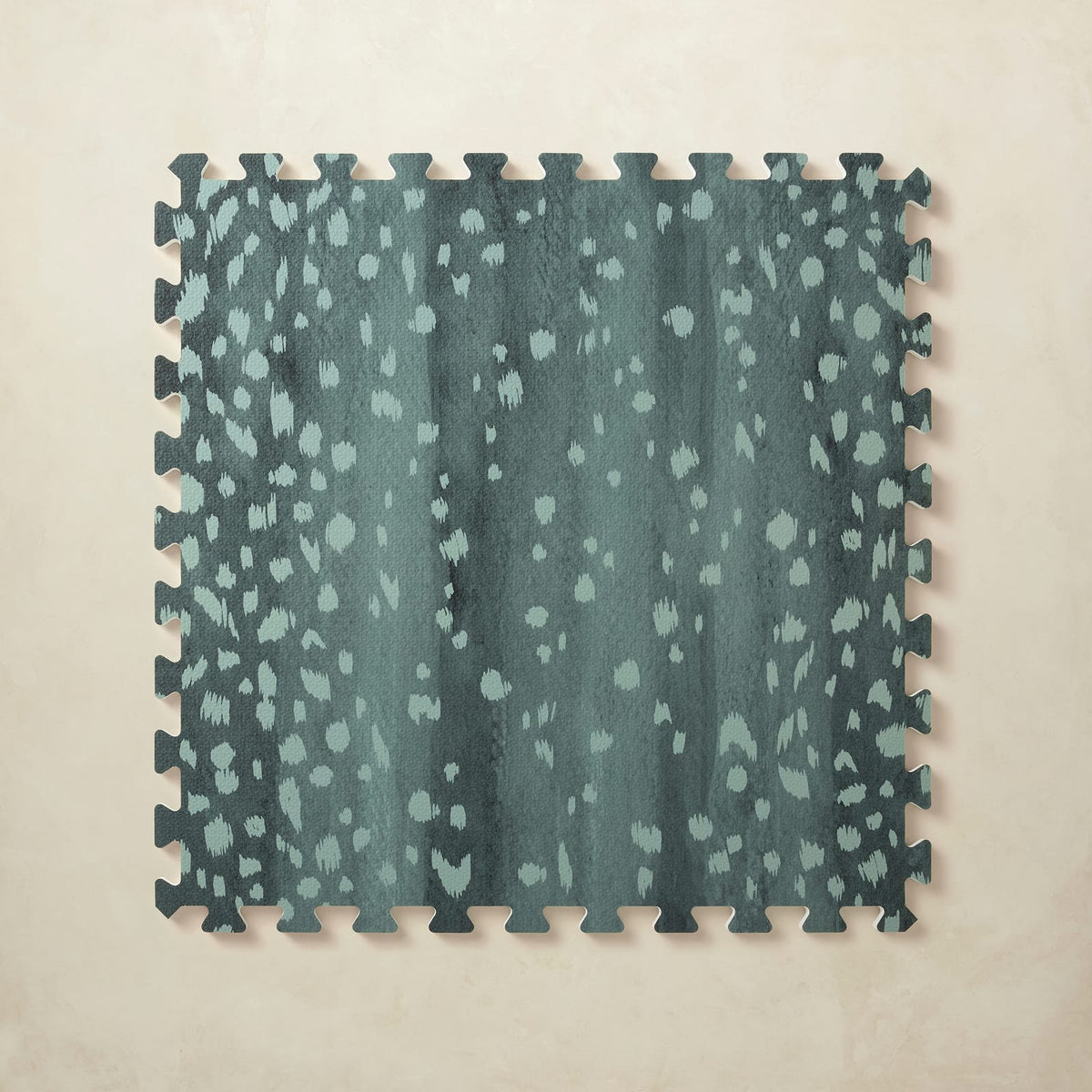 A square interlocking foam play mat tile in deep turquoise with scattered pale aqua fawn spots, shown from above on a light beige background.