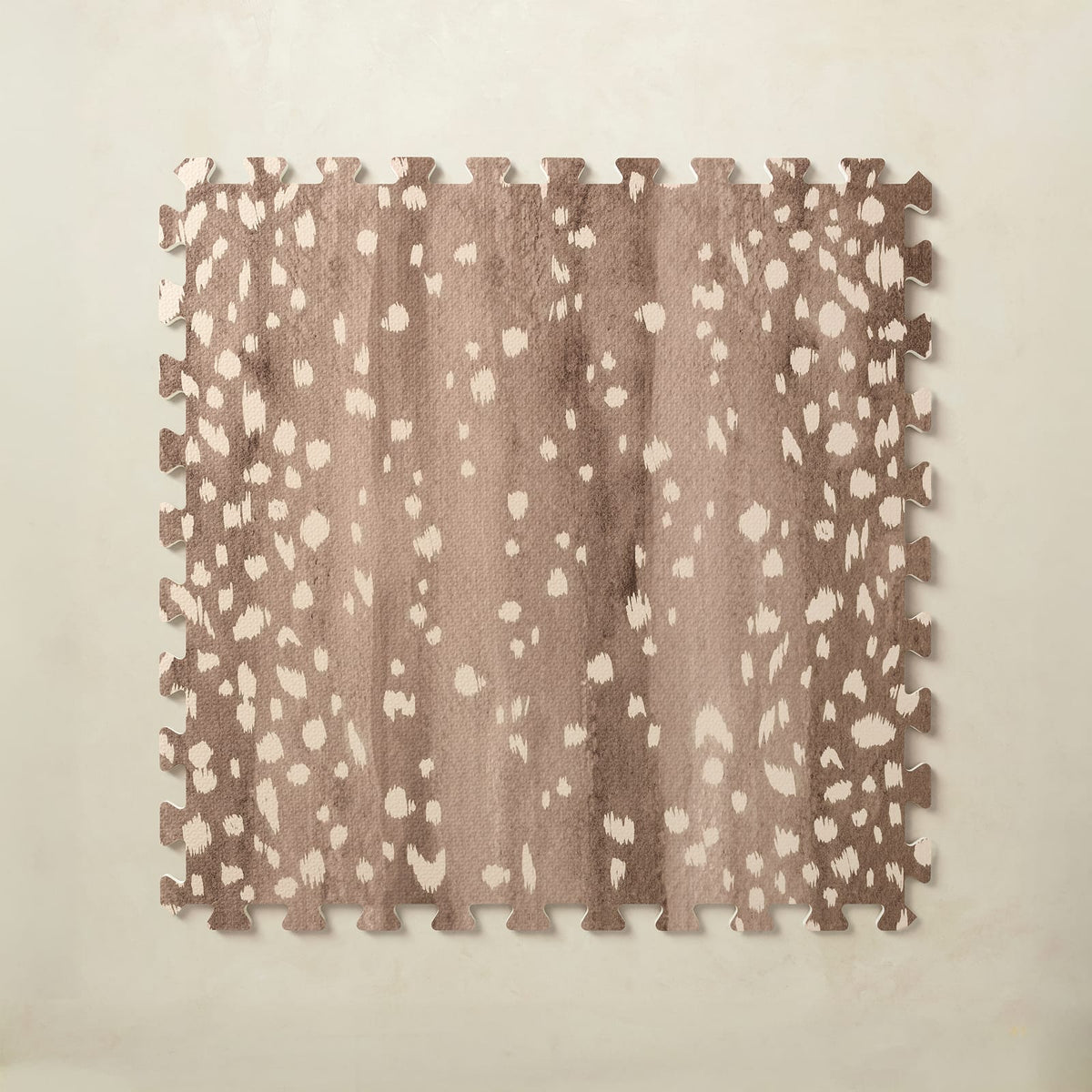 A square interlocking foam play mat tile in walnut brown with scattered hand-painted cream fawn spots, shown from above on a light beige background.