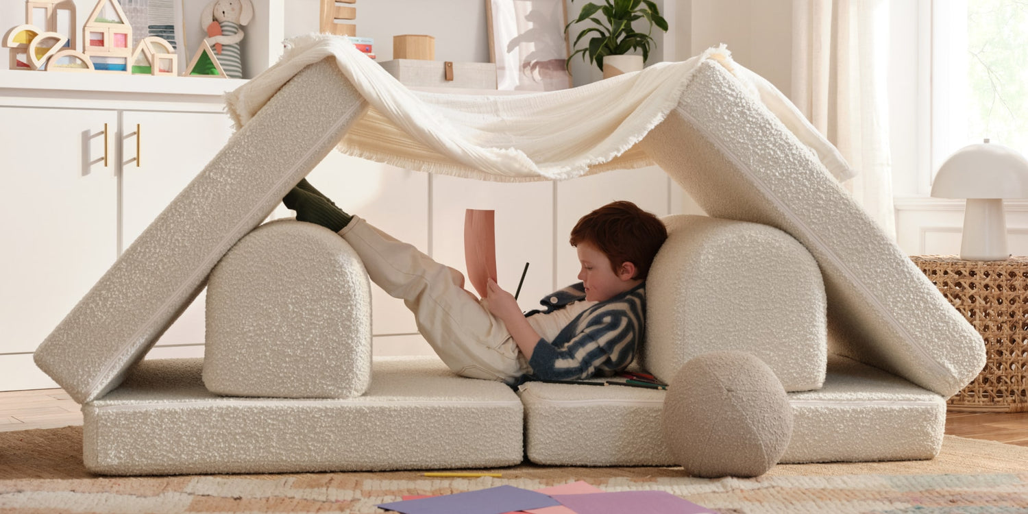 Child playing inside a cushion fort in a cozy living room.