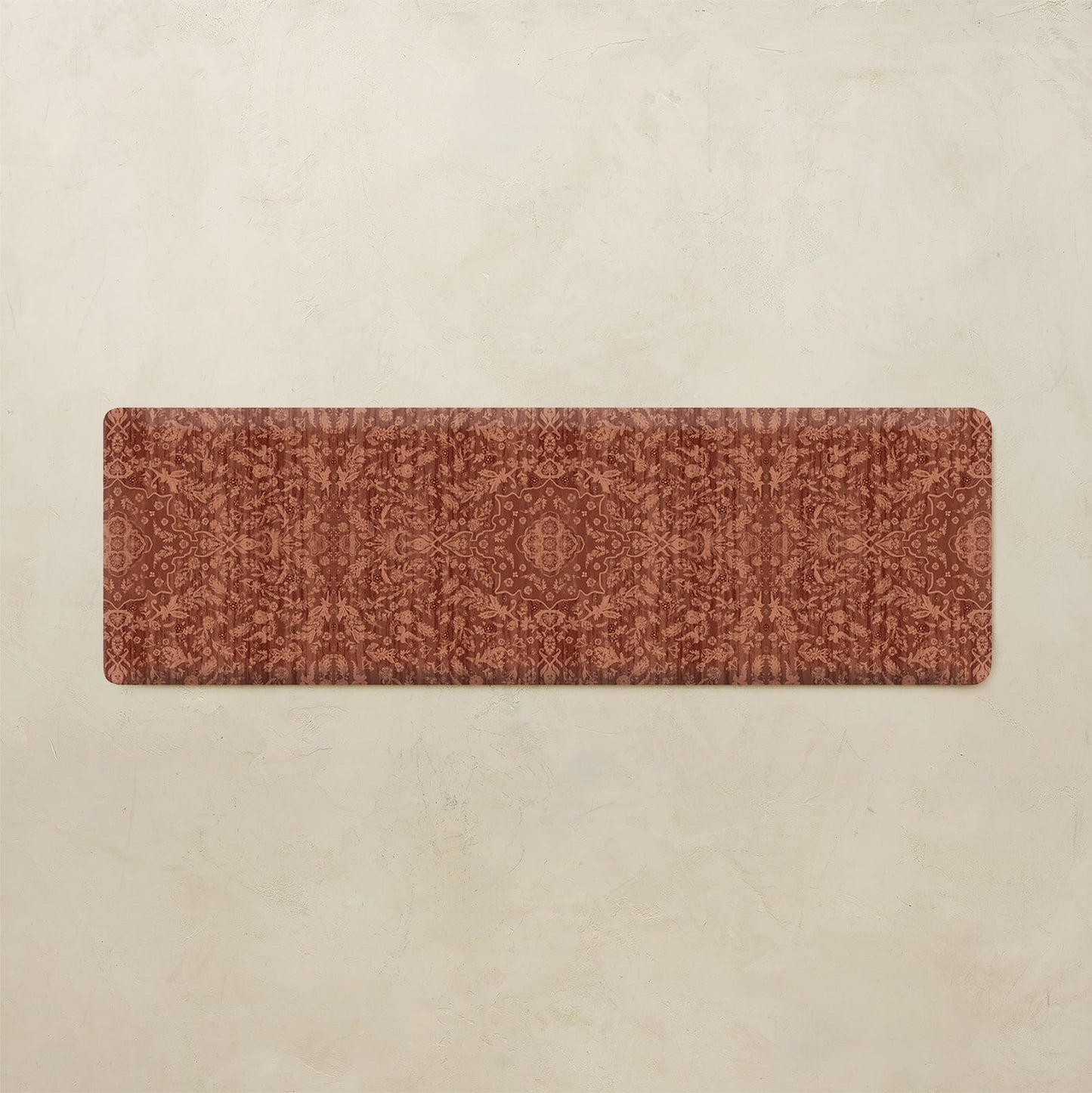 A rectangular floor mat with a distressed, vintage-style damask pattern in terracotta and rust brown, displayed flat against a textured beige background.